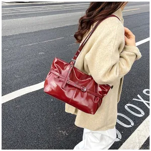 Outdoor street view of burgundy glossy patent leather tote bag with buckle detail