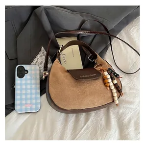 Détails du sac selle minimaliste avec textures mixtes et pompon décoratif en perles