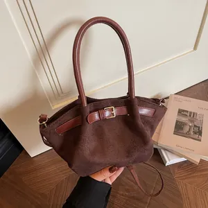 Brown suede crossbody handbag with gold buckle and round handle in a vintage setting