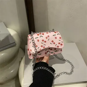Rosa Umhängetasche mit Kirschmuster und Silberkette in einer Lifestyle-Umgebung