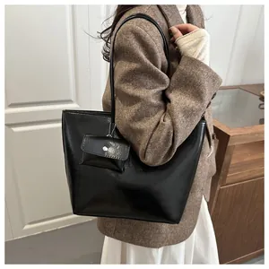 Detail of minimalist black PU leather tote bag with matching detachable hanging pouch