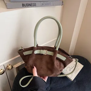 Brown faux suede handbag with green cylindrical handles and adjustable crossbody strap
