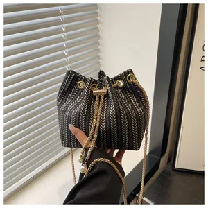 Détail du sac seau tissé à chevrons avec chaîne dorée et grandes perles blanches