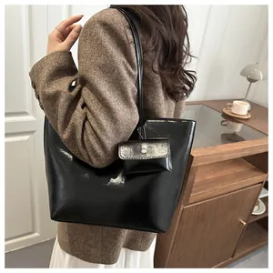 Close-up of black oil-wax leather tote bag and mini pouch worn with tweed blazer