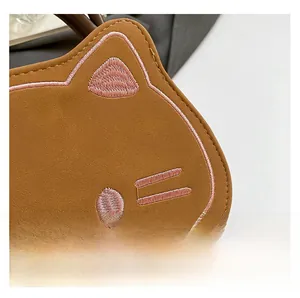 Close-up of brown cat shaped bag showing fine pink embroidery and premium leather texture