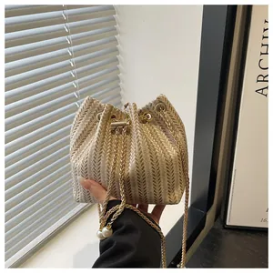 Détail du sac seau tissé avec motif à chevrons, cordon en perles et chaîne dorée