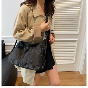 Détail d'un grand sac cabas noir plissé porté par un mannequin en trench-coat beige