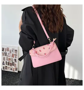 Detailed view of pink crossbody bag with strawberry print and knotted handle detail