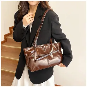Detail of dark brown glossy leather shoulder bag with decorative strap in a lifestyle setting