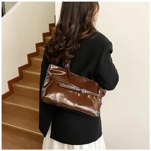 Detail view of dark coffee glossy leather tote bag with decorative buckle and metal eyelets
