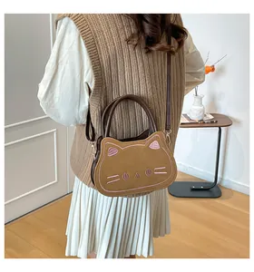 Close-up of cat-shaped crossbody bag with pink embroidery details on brown leather