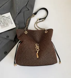 Detail of brown sequin crossbody bag with gold S-logo and metal tassel decoration