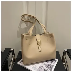 Close-up of beige tote bag featuring gold oval metal buckle and fine faux leather texture