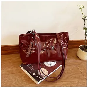 Detail of burgundy glossy leather tote bag with silver eyelets on a fashion magazine