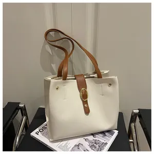 Detail of off-white and brown patchwork tote bag with gold oval metal buckle on a chair