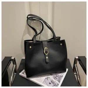 Close-up of black PU tote bag showing gold rivets and oval buckle details on smooth leather