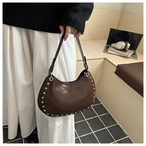 Detail of dark brown hobo bag with golden stud accents and adjustable shoulder strap