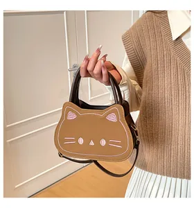Close-up of cat-shaped brown leather handbag with pink facial embroidery and top handle