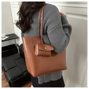 Caramel brown tote bag detail with matching small pouch on model in gray sweater
