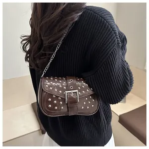 Détail d'un mini sac porté épaule punk marron foncé avec rivets argentés et chaîne
