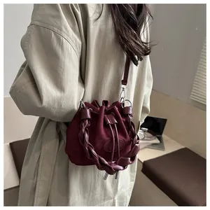 Detailed view of burgundy suede bucket bag with woven handle and drawstring closure