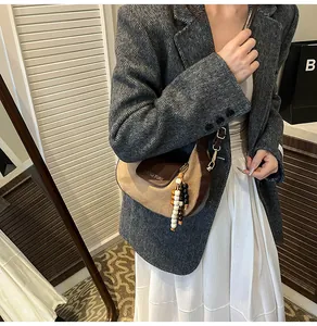 Détail du sac hobo en tissu kaki avec garniture en cuir marron et breloque perlée
