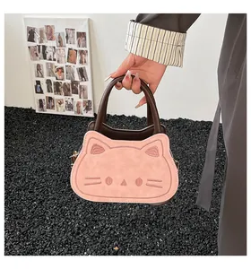 Detail of pink cat-shaped handbag with embroidery and contrasting brown leather handles