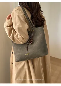 Gros plan d'un sac cabas en cuir vert olive avec breloque en résine et logo élégant