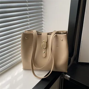 Elegant beige faux leather tote bag with gold buckle on a minimalist windowsill