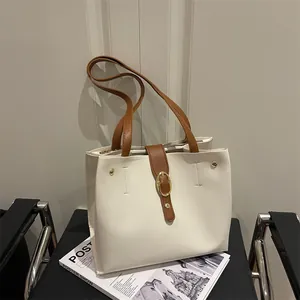 Retro cream faux leather tote bag with brown contrast straps and gold buckle on a chair