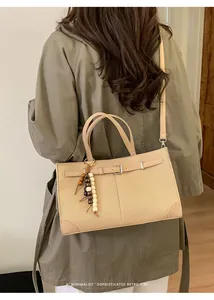 Detailed back view of a minimalist beige woven tote bag worn with an olive trench coat