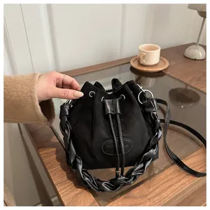 Detailed close-up of a black suede bucket bag featuring woven handle and silver eyelets