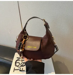 Détail du sac demi-lune en daim marron foncé avec perles en bois et zip