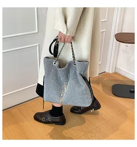 Detalle del bolso bandolera de lentejuelas plateadas con cadena dorada y borla elegante