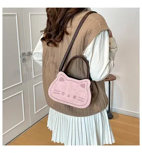 Detail view of pink cat-shaped crossbody bag with embroidered facial features and brown straps