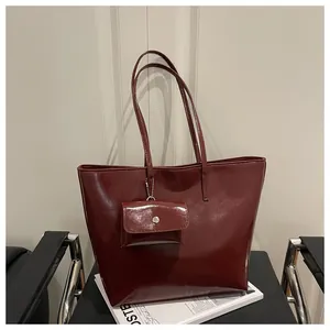 Close-up of wine red patent leather tote bag with matching coin pouch and glossy finish