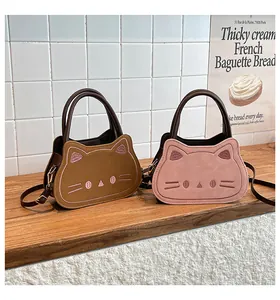 Detail view of cat-shaped crossbody bags in brown and pink with golden hardware