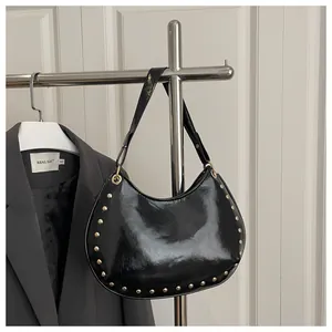 Detailed view of black patent leather shoulder bag with gold studs and blazer outfit