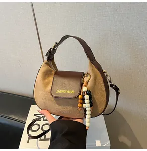 Détail du sac rétro en patchwork avec cuir marron, texture daim et gland en perles