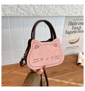 Detailed embroidery of cat face on pink suede crossbody bag with brown handles