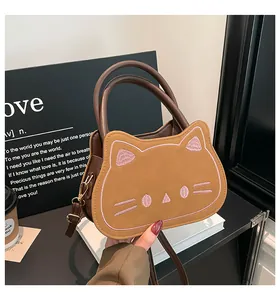 Macro view showing detailed pink cat embroidery and texture on brown crossbody bag