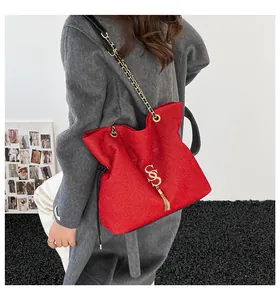 Detalle de bolso tote rojo texturizado con logo SS dorado y elegante flequillo