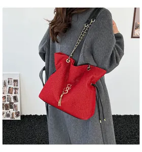 Detalle de bolso rojo texturizado con cadena dorada y colgante de borla con estilo