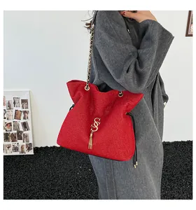 Detalle del bolso rojo con textura, cadena dorada y un elegante colgante de borla