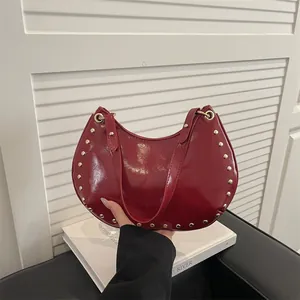 Red glossy crescent shoulder bag with golden rivets and a stylish vintage design