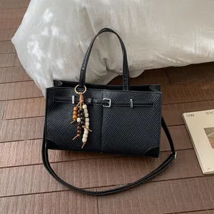 Black twill textured tote bag with bead pendant and adjustable strap for commuting