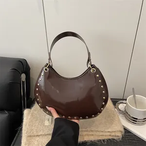 Dark brown crescent shoulder bag with gold studs and glossy leather on knit background