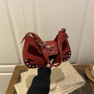 Red retro motorcycle underarm bag with silver rivets and suede patches in a lifestyle setting