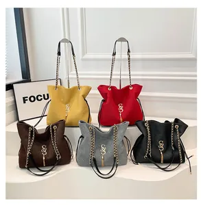 Detalle de cinco elegantes bolsos tipo cubo con logo metálico y borlas de flecos