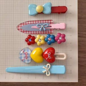 Detail view of five colorful hair clips with bow and flower designs on a scale ruler